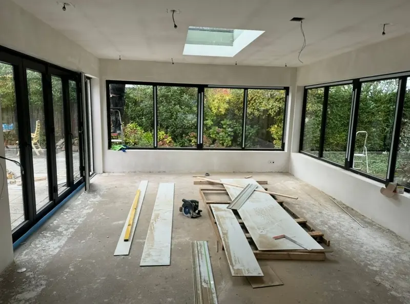Uitbouw in Breda in de afbouwfase: gestucte wanden, zwarte kozijnen over twee gevels, lichtstraat in het dak en vouwpui naar de tuin